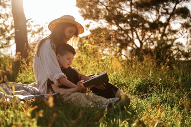 Oturup kitap okuyorum. Anne ve oğlu ormanda beraberler..