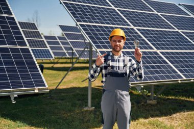 Geleneksel ampul elinde. Gündüz vakti fotovoltaik güneş panelleri olan bir mühendis..