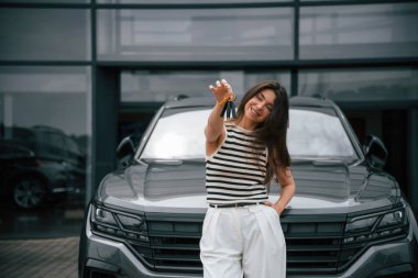 Yeni arabanın anahtarlarını. Mutlu sahip. Çekici genç bayan dışarıda, yepyeni arabasının yanında..