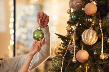 Ağaca yeni yıl süsü koyan erkek ve kadınların ellerini yakından görebiliyoruz..