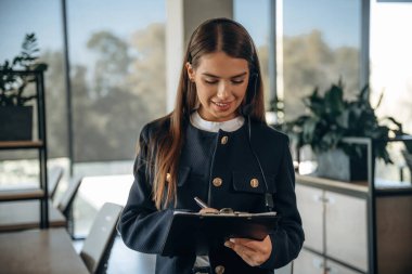 Siyah not defteri ve elinde bir kalem. Kadın ofiste çalışıyor..