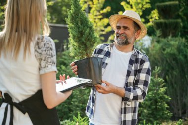 Tencereye bitki koymak. Kadın ve erkek bahçede birlikte çalışıyorlar..