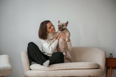 Ön manzara, küçük kanepede oturmak. Genç kadın köpeğiyle evde..