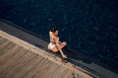 Yüzme havuzunun yanında. Beyaz bikinili kadın..