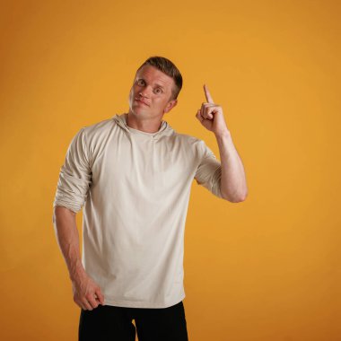 Yukarı bak, işaret et, boşluğu kopyala. Adam stüdyoda arka plana karşı..