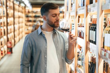 İçkiyle bardağa bakıyorum. Adam dükkanda şarap seçiyor..