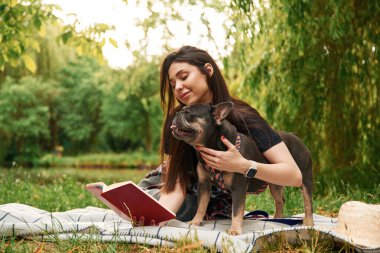 Kırmızı defter, çimlerin üzerinde. Genç güzel bayan köpeğiyle birlikte parkta..
