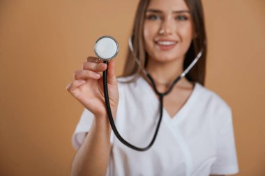 Steteskop elinde. Genç ve güzel bir bayan stüdyoda arka plana karşı..