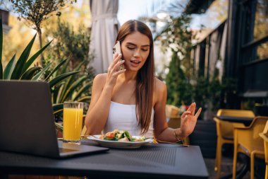 Modern akıllı telefon, masanın yanında. Güzel genç bayan restoranın dışında..