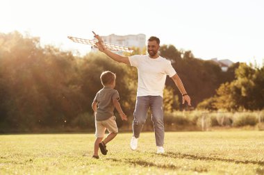 Koşmak, eğlence. Baba ve oğul oyuncak uçakla sahadalar..
