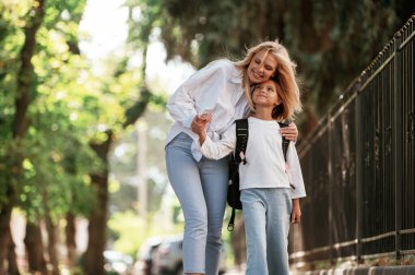 Ön manzara, yürüyüş. Annesiyle okul kızı dışarıda beraberler..