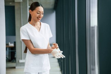 İşe hazırlanıyorum, eldiven giyiyorum. Beyaz önlüklü kadın doktor içeride..