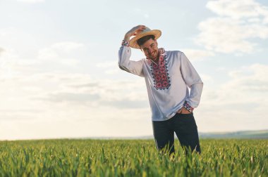 Hasır şapkayı çıkarıyorum. Ukrayna nakışlı gömlekli adam yaz günü tarımsal alanda..