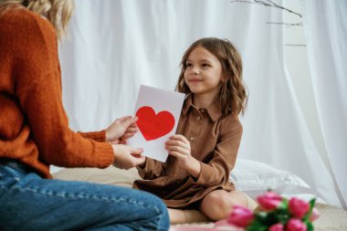 Anneler günü için kırmızı kağıt kalp şeklinde bir hediye. Kızı olan kadın ebeveyn evde..