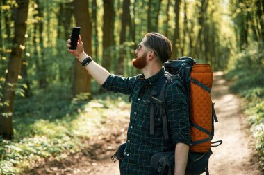 Elimde telefon var. Sakallı adam gündüz vakti ormandadır..
