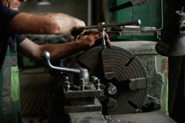 Odaklanmış manzara. Atölyede endüstriyel makineleri çalıştıran işçilerin yakın çekimi.