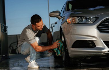 Araba yıkama, cilalama işi. Adam dışarıda otomobille geziyor..