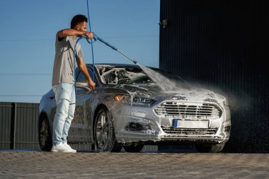 Köpük yıkılıyor, otomobil sabun içinde. Adam dışarıda arabasıyla bekliyor..