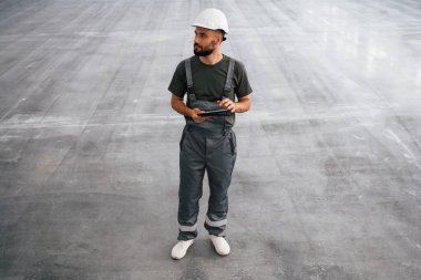 Önden bak, elinde dijital tabletle. Erkek işçi boş depoda..