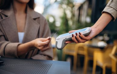 Kafede yemek parasını kredi kartıyla ödeyen kadın. Kablosuz para transferi kavramı.