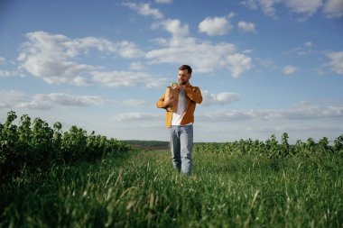 Elinde ürünler olan bir alışveriş çantası. Yakışıklı adam gün içinde tarım alanında olur..