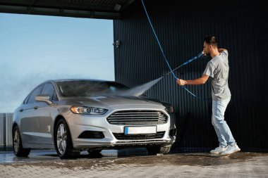 Otomobil yıkama, adam dışarıda arabasıyla bekliyor..