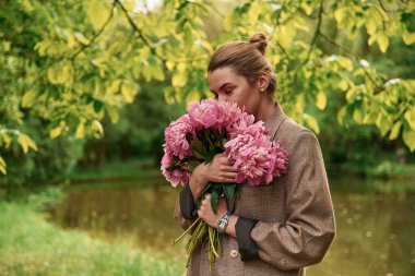 Hediye kavramı. Güzel genç bir kadın şakayık çiçekleriyle parkta..