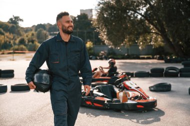 Aracın ve ağaçların karşısında duruyor. Erkekler açık havada, kart yarışı gebeliği..