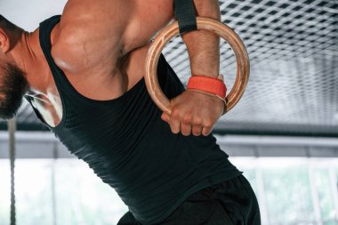 Kaldırıyorum. Atletizm yüzükleri kullanan güçlü bir adama yakından bakın..