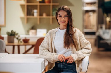 Güzel, gülümseyen kadın mutfaktaki masanın yanında oturuyor..