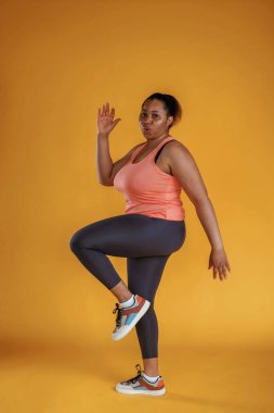 Fitness yapıyorum. Afrikalı Amerikalı kadın sarı arka planda stüdyoda..