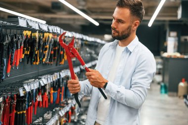 Kırmızı boru anahtarı. Adam hırdavatçıda..