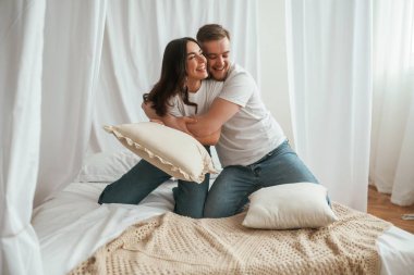 Yumuşak yastıklar ellerinde, oynuyorlar. Genç çift evde birlikteler..