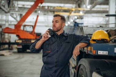 Mola veriyoruz, bir bardak içkiyle. Erkek işçi, modern depo veya imalat şirketinde çalışıyor..