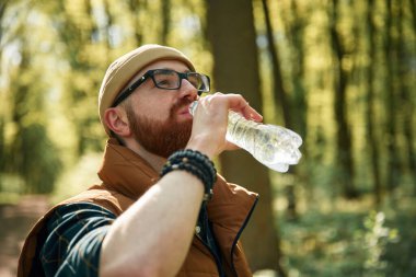 Su içiyorum. Sakallı adam gündüz vakti ormandadır..