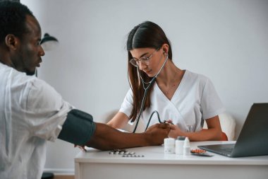 Sağlık sigortası gebeliği. Kadın doktor bir erkeğin kan basıncını ölçer..