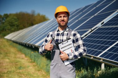 Photovoltaik güneş panelleri olan neşeli mühendis gündüz vakti dışarıda..
