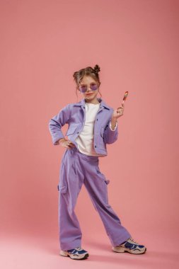 Elindeki renkli şeker. Şirin küçük kız pembe arka plana karşı..