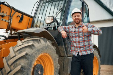 Araca yaslan. Adam traktörle birlikte. Tarım işçisi.