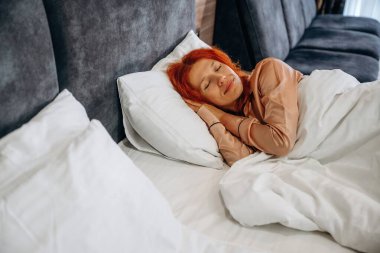 Rahat bir yatakta, pijamayla uyuyorsun. Kadın otel odasında, modern iç mekan..