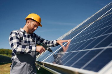 Neredeyse bitti, matkap kullanarak kurulum yapılıyor. Gündüz vakti fotovoltaik güneş panelleri olan bir mühendis..