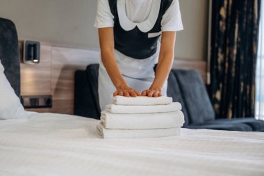 Yepyeni temiz havlular. Hizmetçi modern otel odasında çalışıyor..