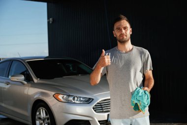 Ellerinde bezle. Adam dışarıda otomobille dolaşıyor..