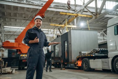 Evraklar not defterinde. Erkek işçi, modern depo veya imalat şirketinde çalışıyor..