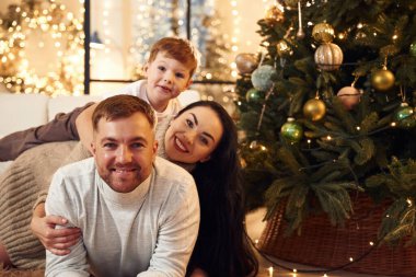 Güzel dekore edilmiş ağaç. Mutlu bir aile yeni yılı evde kutluyor..