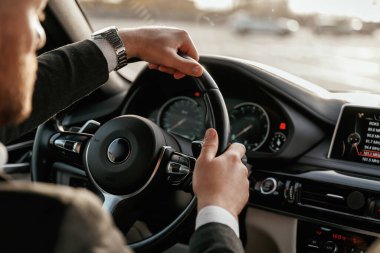 Direksiyona yakından bak. Siyah takım elbiseli adam arabada oturuyor..