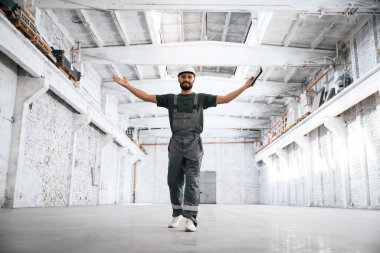 Eller yanda, geniş alan görünüyor. Erkek işçi boş depoda..