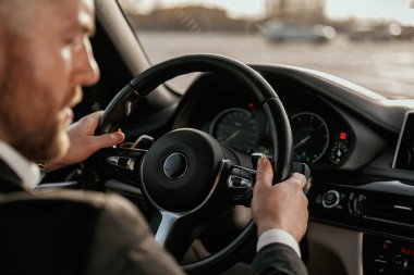 Direksiyona yakından bak. Siyah takım elbiseli adam arabada oturuyor..