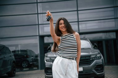 Yeni arabanın anahtarlarını. Mutlu sahip. Çekici genç bayan dışarıda, yepyeni arabasının yanında..