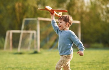 Oyuncak uçakla koşuyor. Şirin, mutlu küçük çocuk açık arazide..
